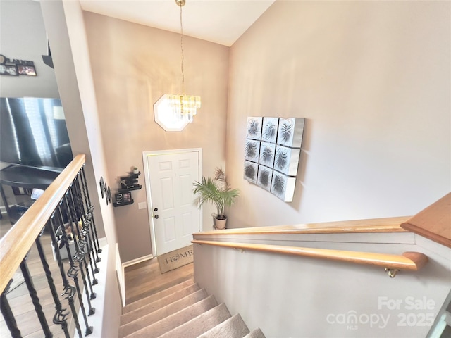 staircase featuring an inviting chandelier, wood-type flooring, and a high ceiling