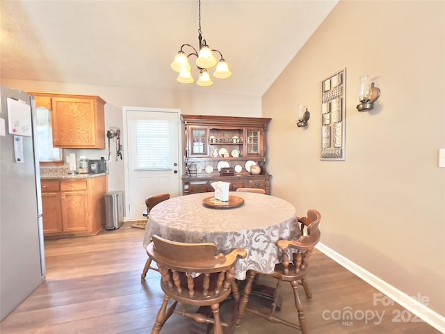 dining area with lofted ceiling, hardwood / wood-style flooring, and a chandelier