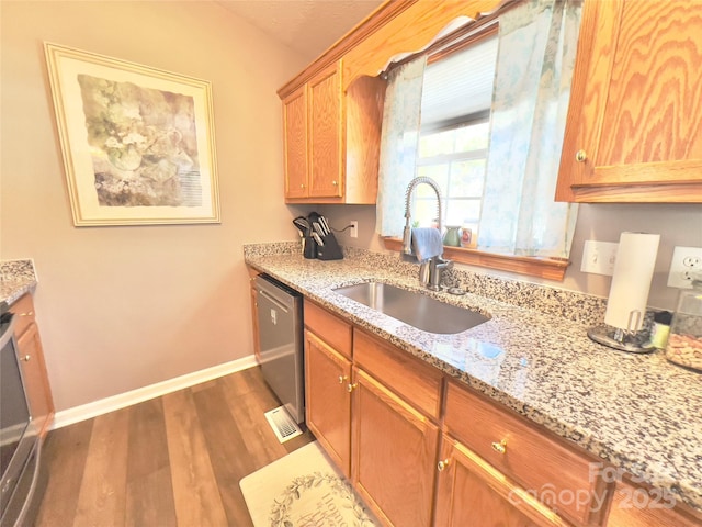 kitchen with sink, light stone countertops, dark hardwood / wood-style floors, and dishwasher