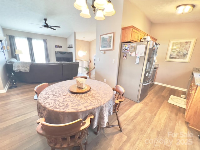 dining space with ceiling fan with notable chandelier and light hardwood / wood-style floors