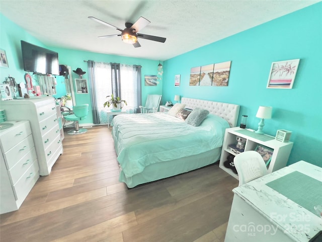 bedroom featuring hardwood / wood-style flooring, ceiling fan, and a textured ceiling