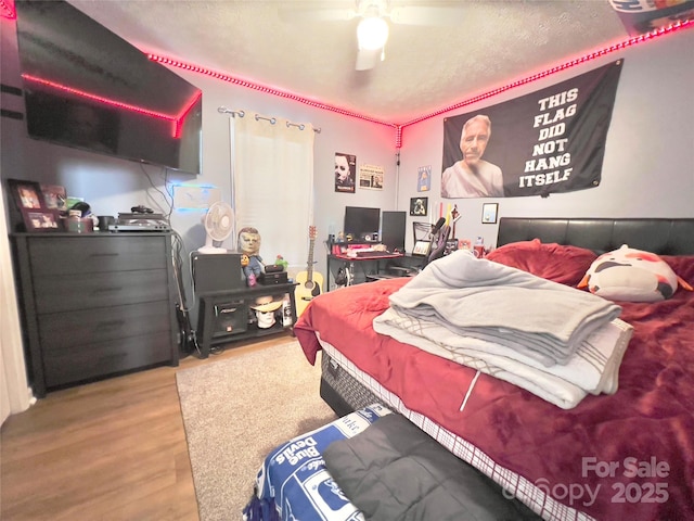 bedroom with hardwood / wood-style flooring, ceiling fan, and a textured ceiling