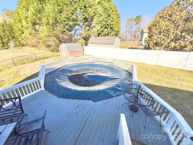 wooden terrace featuring a covered pool, a lawn, and a shed