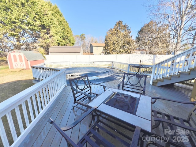 wooden deck with an outdoor fire pit and a shed