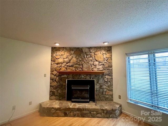 room details featuring a stone fireplace, a textured ceiling, and hardwood / wood-style flooring