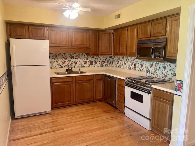 kitchen with sink, white appliances, ceiling fan, a textured ceiling, and light hardwood / wood-style flooring