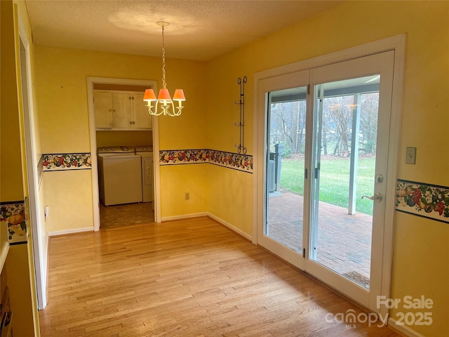 unfurnished dining area featuring an inviting chandelier, washing machine and clothes dryer, light hardwood / wood-style flooring, and a textured ceiling