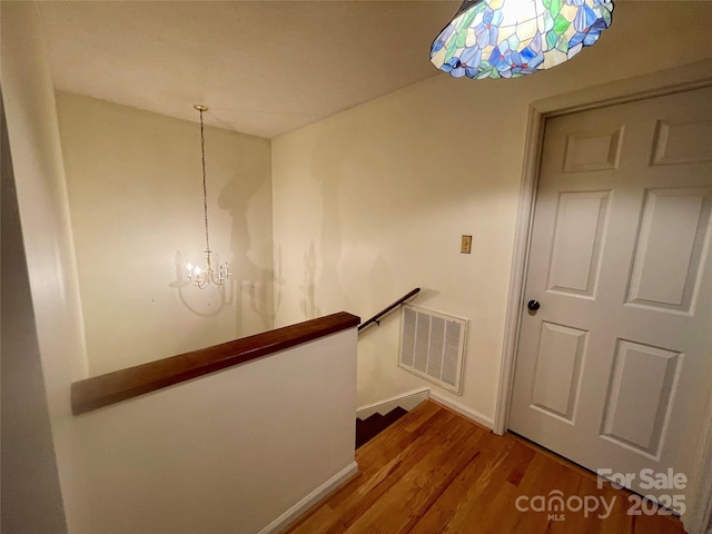 stairs with hardwood / wood-style floors and a chandelier