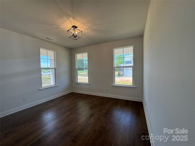 unfurnished room with dark wood finished floors, baseboards, a chandelier, and visible vents