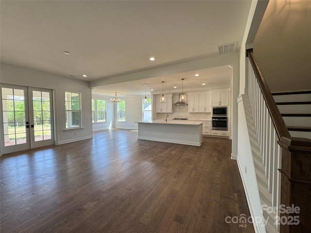 unfurnished living room with french doors, dark wood-style flooring, visible vents, recessed lighting, and a notable chandelier