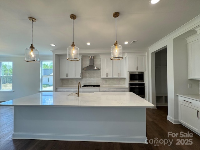 kitchen with a sink, wall chimney range hood, white cabinetry, crown molding, and appliances with stainless steel finishes