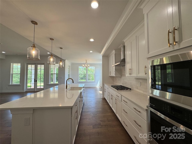 kitchen featuring recessed lighting, stainless steel appliances, backsplash, wall chimney range hood, and a sink