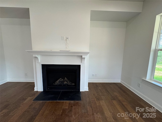 interior details with a fireplace with flush hearth, baseboards, and wood finished floors