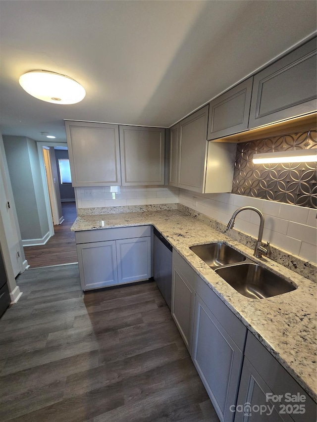 kitchen with sink, gray cabinetry, dark hardwood / wood-style flooring, decorative backsplash, and light stone counters