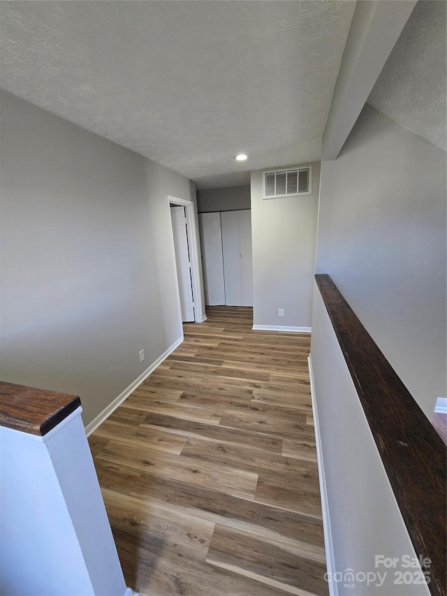 hall with hardwood / wood-style flooring and a textured ceiling