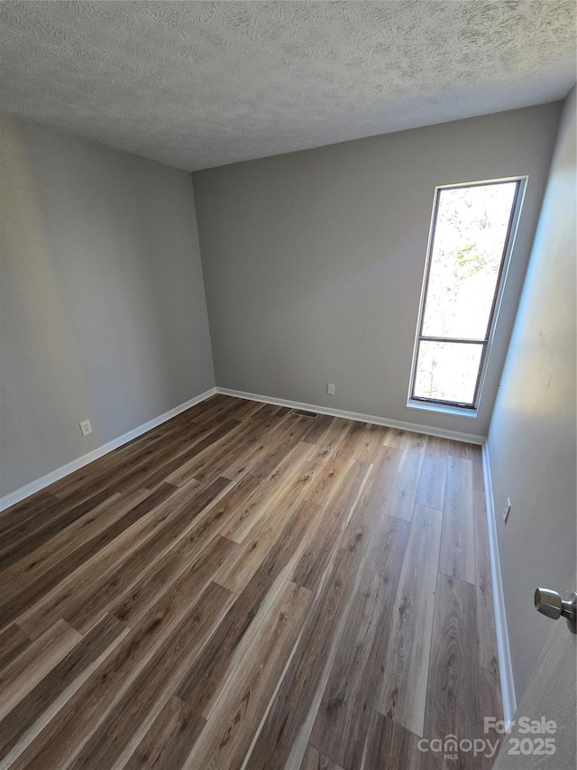 unfurnished room with dark hardwood / wood-style flooring and a textured ceiling