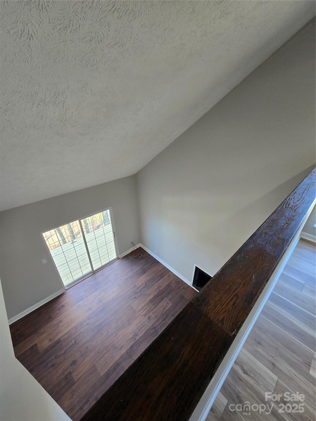 interior space with hardwood / wood-style flooring, lofted ceiling, and a textured ceiling