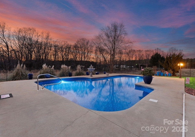 pool at dusk featuring a patio