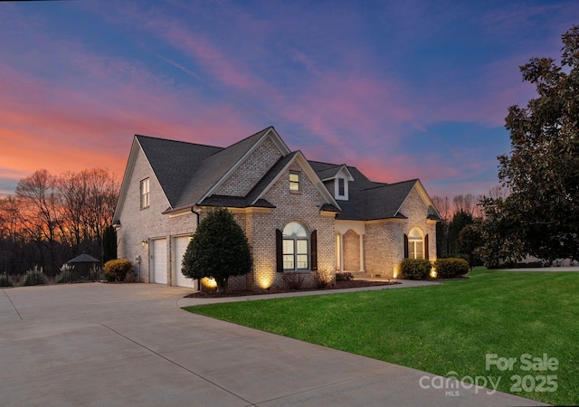 french country inspired facade featuring a yard and a garage