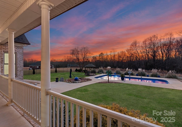 pool at dusk featuring a yard and a patio area