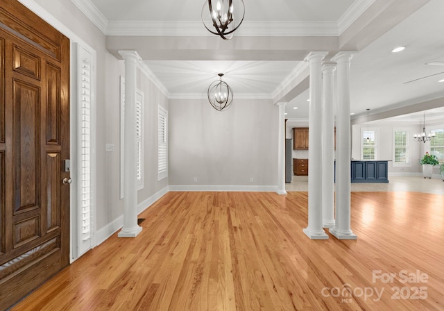 entrance foyer with decorative columns, crown molding, a notable chandelier, and light hardwood / wood-style floors