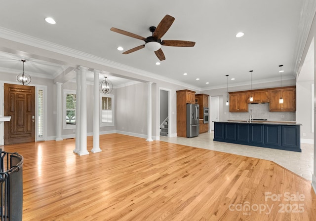 unfurnished living room featuring crown molding, light hardwood / wood-style floors, and ornate columns