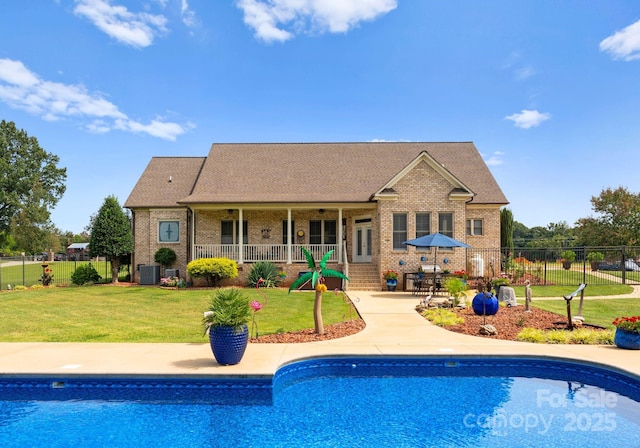 rear view of house with a fenced in pool, a patio, central AC, and a lawn