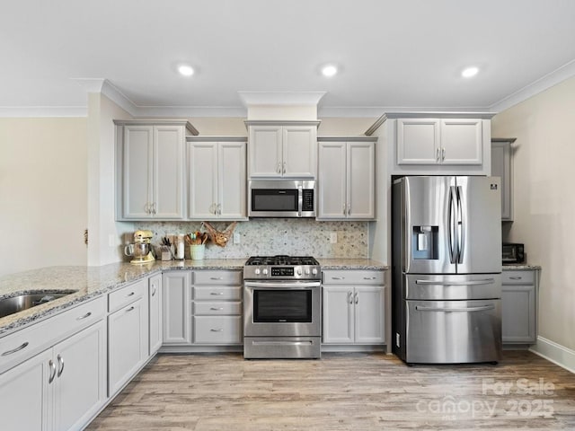 kitchen with stainless steel appliances, ornamental molding, light stone counters, and decorative backsplash