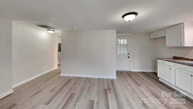 kitchen featuring dark stone counters, white cabinets, and light wood-type flooring