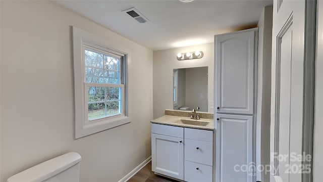 bathroom featuring vanity, hardwood / wood-style flooring, plenty of natural light, and toilet