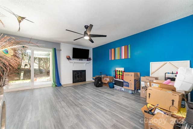 interior space featuring a fireplace, wood-type flooring, a textured ceiling, and ceiling fan