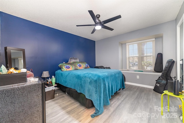 bedroom with hardwood / wood-style flooring, a textured ceiling, and ceiling fan