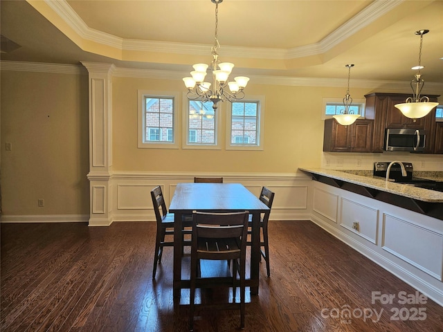 dining area featuring a notable chandelier, dark hardwood / wood-style floors, ornamental molding, and a raised ceiling