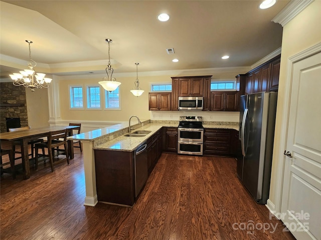 kitchen featuring pendant lighting, appliances with stainless steel finishes, kitchen peninsula, and sink