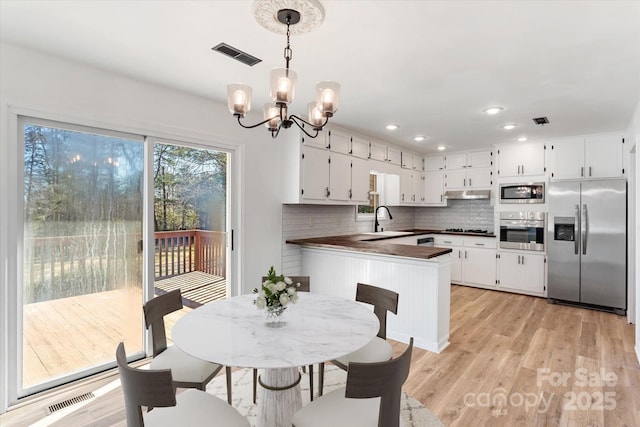 dining room featuring sink, a chandelier, and light hardwood / wood-style flooring