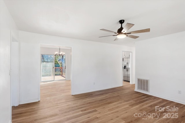 spare room with ceiling fan with notable chandelier and light wood-type flooring