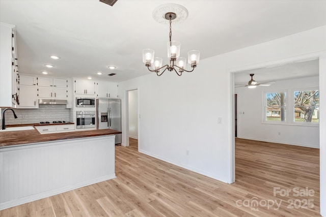 kitchen with decorative light fixtures, tasteful backsplash, white cabinetry, sink, and stainless steel appliances