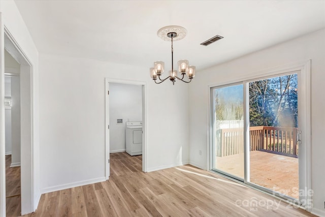 unfurnished dining area with a chandelier, washer / dryer, and light wood-type flooring