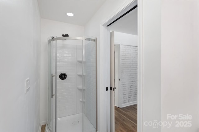 bathroom with hardwood / wood-style flooring and a shower with shower door