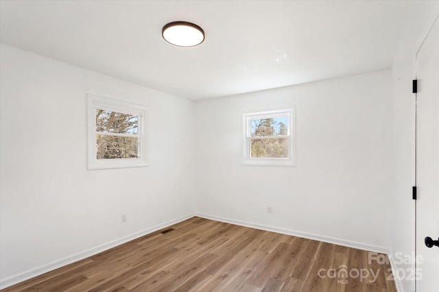 spare room with a healthy amount of sunlight and hardwood / wood-style floors