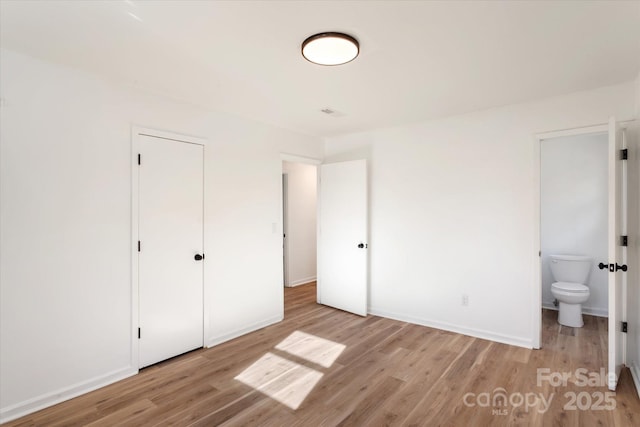 unfurnished bedroom with ensuite bath and light hardwood / wood-style flooring