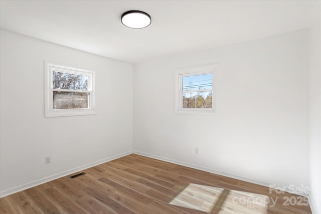 spare room with a wealth of natural light and wood-type flooring