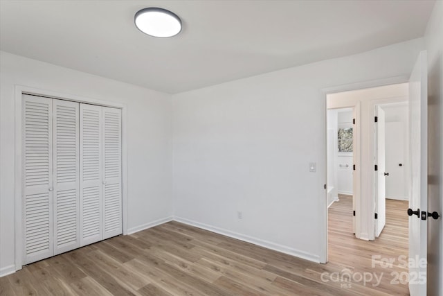 unfurnished bedroom with a closet and light wood-type flooring