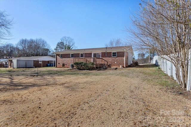 back of property featuring a wooden deck and a yard