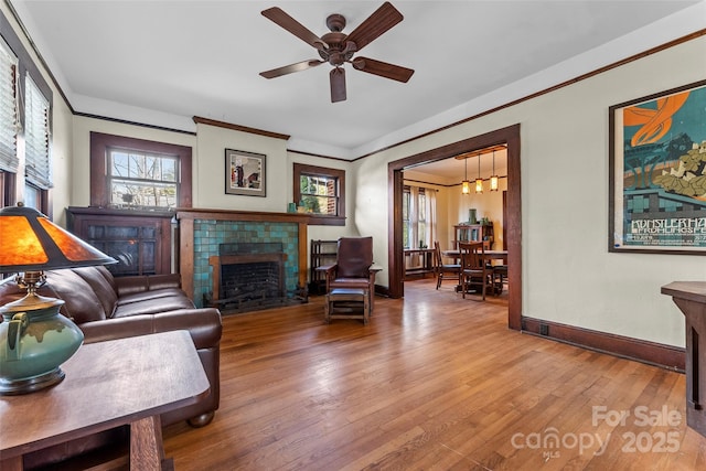 living room featuring hardwood / wood-style flooring, ornamental molding, ceiling fan, and a fireplace