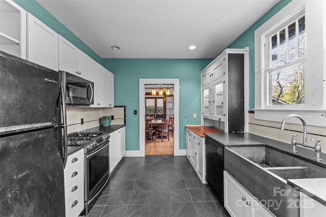 kitchen with tasteful backsplash, sink, white cabinets, and black appliances