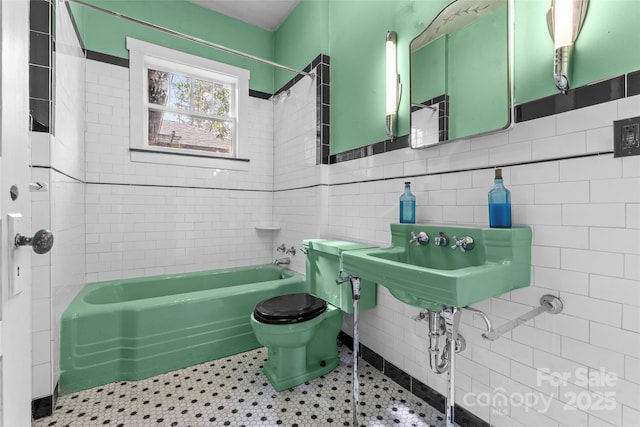 bathroom featuring tile walls, tiled shower / bath combo, and toilet