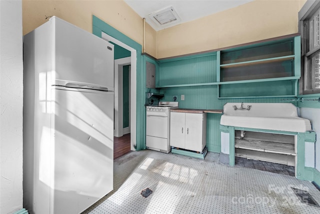 kitchen featuring electric stove, green cabinetry, and refrigerator