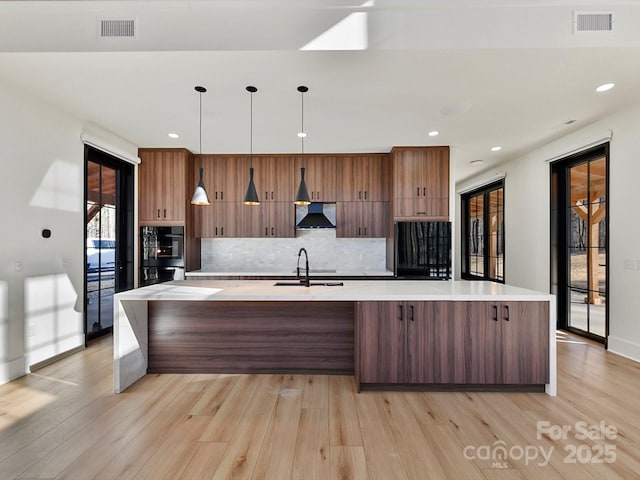 kitchen featuring a large island, sink, pendant lighting, and range hood