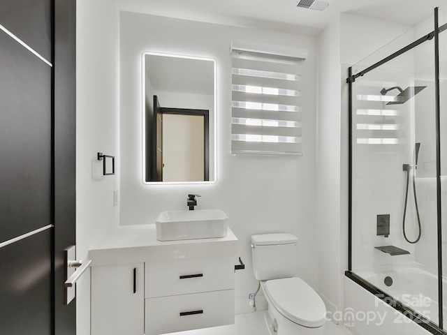 full bathroom with vanity, bath / shower combo with glass door, and toilet